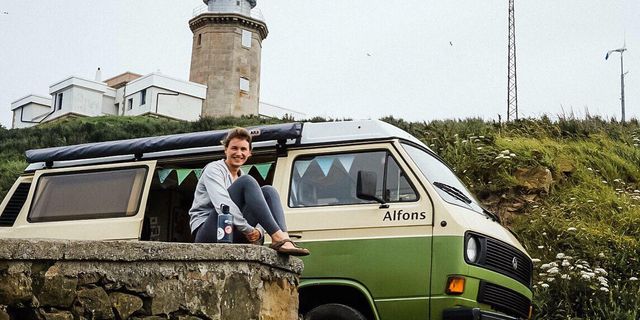 A woman sitting outside in front of a camper van