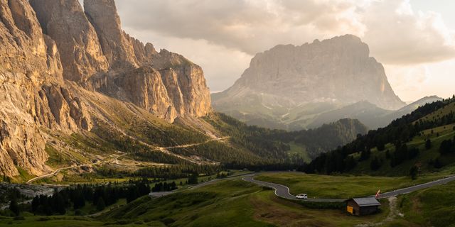 Eine Luftaufnahme von einer Straße in den Dolomiten. Aus der Ferne sieht man, dass ein Camper die Straße entlangfährt.