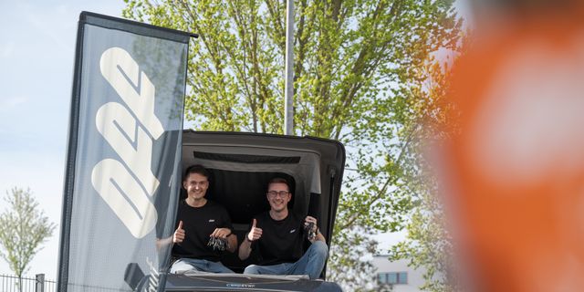 Zwei junge Männer beim Campingbus kaufen im Dachzelt eines Off Campers mit Autoschlüsseln in der Hand