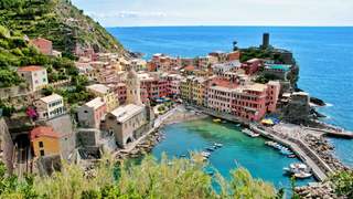 Camping Cinque Terre: Ein Dorf der Cinque Terre von oben fotografiert mit bunte Häuschen, einem Hafen und dem Meer im Hintergrund.