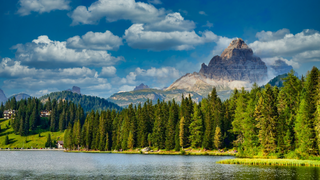 Der Misurinasee in den Dolomiten in Südtirol ist ein toller Geheimtipp: Ein Foto vom Ufer des Sees zeigt das klare Wasser, umgeben von Wiesen, Bäumen und Bergen