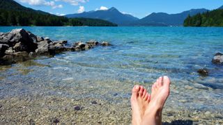 Entspannung pur beim Camping am Walchensee: Füße im Wasser am Seeufer des Walchensees mit Bergkulisse im Hintergrund