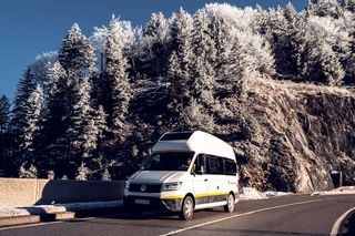 VW Grand California fährt durch Winterlandschaft