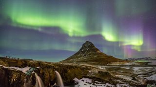 Nordlichter über bergiger Landschaft