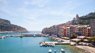 Portovenere ist ein Geheimtipp in Italien: Bunte Häuschen in der Sonne neben dem Hafen der Stadt, in dem einige Schiffe stehen.