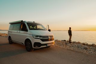 Camper und Mann stehen vor Meer Sonnenuntergang