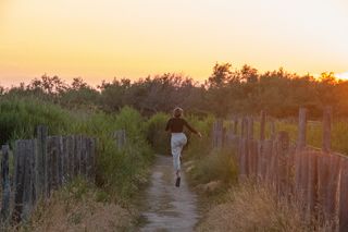 Girl jumping on a path along the coast in Corsica at sunset