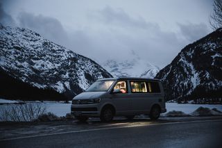 VW California Ocean steht vor verschneiten Bergen