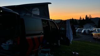 Schwarzer Camper bei Sonnenuntergang auf Campingplatz