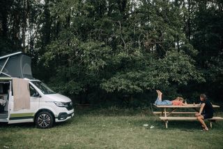 Child with father next to their camper on a campsite in the forest