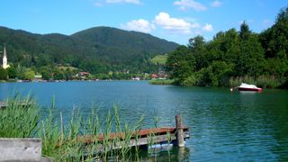 Das Ufer des Schliersees in Bayern mit einem Steg und Wäldern im Hintergrund