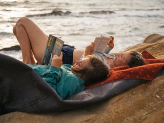 Zwei Frauen liegen am Strand und lesen.