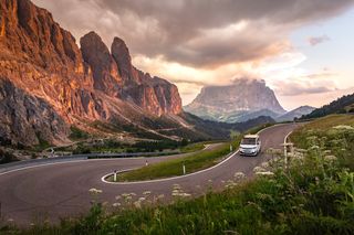 Ein VW Camper fährt eine kurvige Bergstraße entlang.