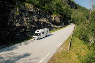 Ein weißes Wohnmobil von Off Campers fährt eine Straße in Norwegen entlang