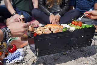 Kleiner Grill am Strand mit Gemüse und Fleisch drauf