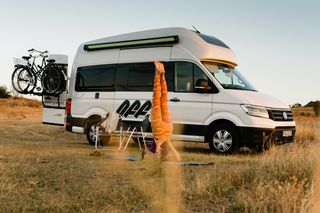 Eine Frau macht Yoga vor einem Grand California 600 Camper von Off.