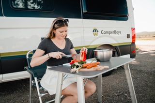 Frau macht Essen vor einem Campervan