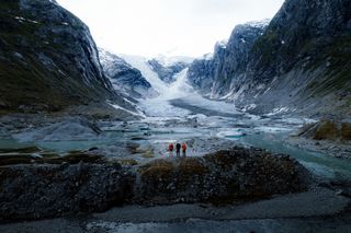 Drei Männer stehen in einem Gletscher in Norwegen in Wanderausrüstung.