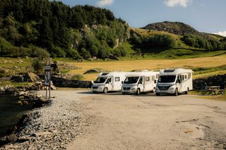 Drei Wohnmobile stehen nebeneinander auf einem Stellplatz in Norwegen im Grünen. Norwegen Geheimtipps findest du in diesem Artikel.