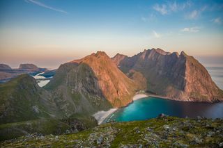 Eine Insel der Inselgruppe Vesterålen in Norwegen von oben. Man sieht Berge, Strand und blaues Meer.