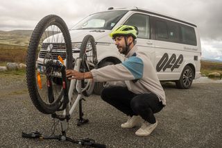 Mann repariert Fahrrad vor Camper