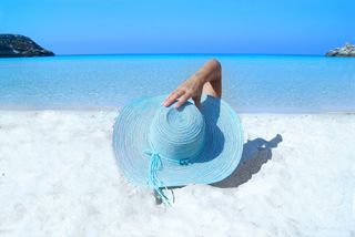 Person mit Sonnenhut die am Strand liegt