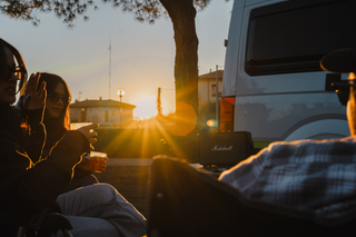 Freunde sitzen in der Abendsonne vor dem Camper