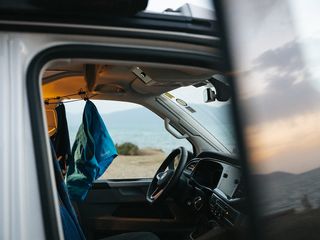 Ein Camper steht beim Überwintern in Griechenland am Meer. Im Innern trocknen an einer Wäscheleine Badesachen.