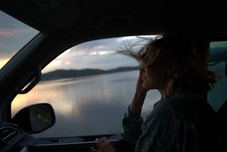 Woman with flowing hair looks out of the camper window