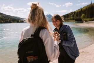 Two young women laugh at each other while hiking at Walchensee