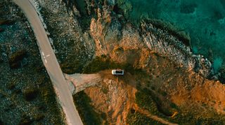 A van is driving down a road by the coast. 